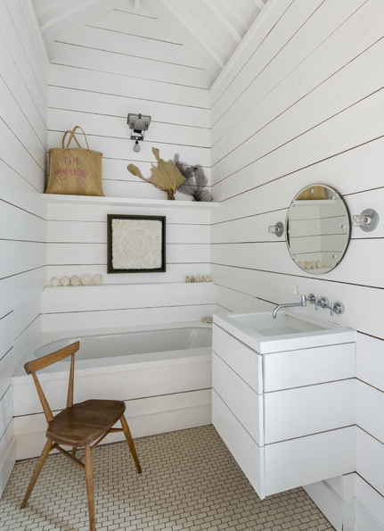 The bathroom is clad in white painted timber boards.