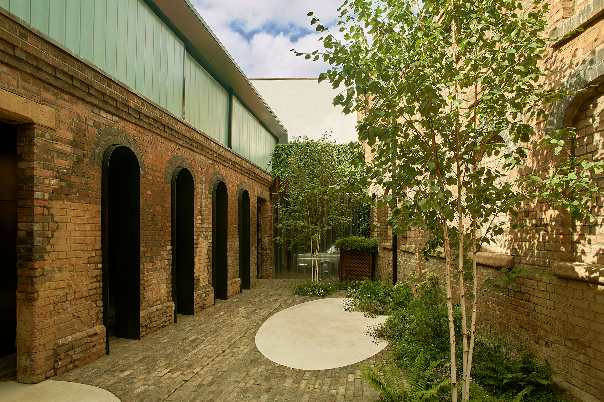 Original brickwork openings have been lined in rolled steel to provide an arcaded podium onto the main cobbled courtyard.  This contrasts with lightness of the cast glass and steel monolith of the first floor.