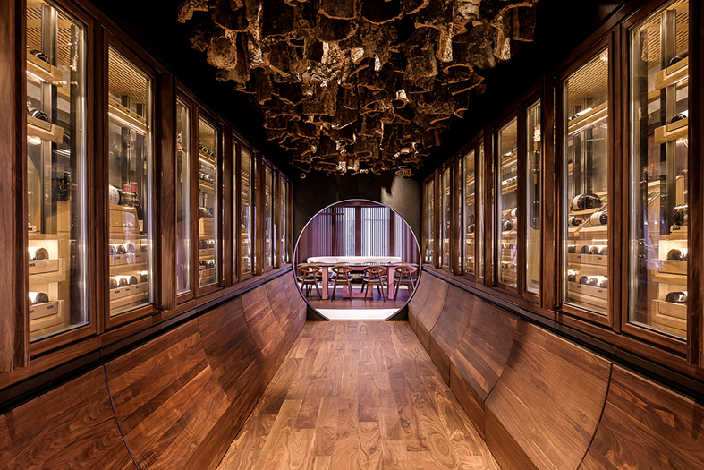 The climatically controlled cabinets of the cellar have been detailed in timber with curved wine display drawers below and a ceiling hung with raw bark from cork trees.