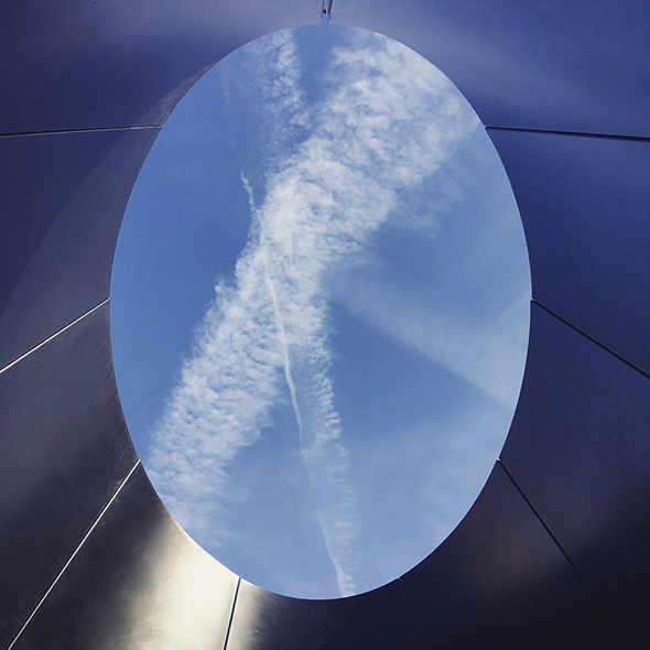 A double curvature oculus formed in the steel roof panels creates an opening that frames the sky over the roof garden.