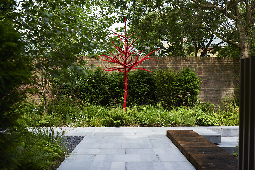 A metal tree sculture by Jivko Sedlarski is silhouetted against the yew hedge.