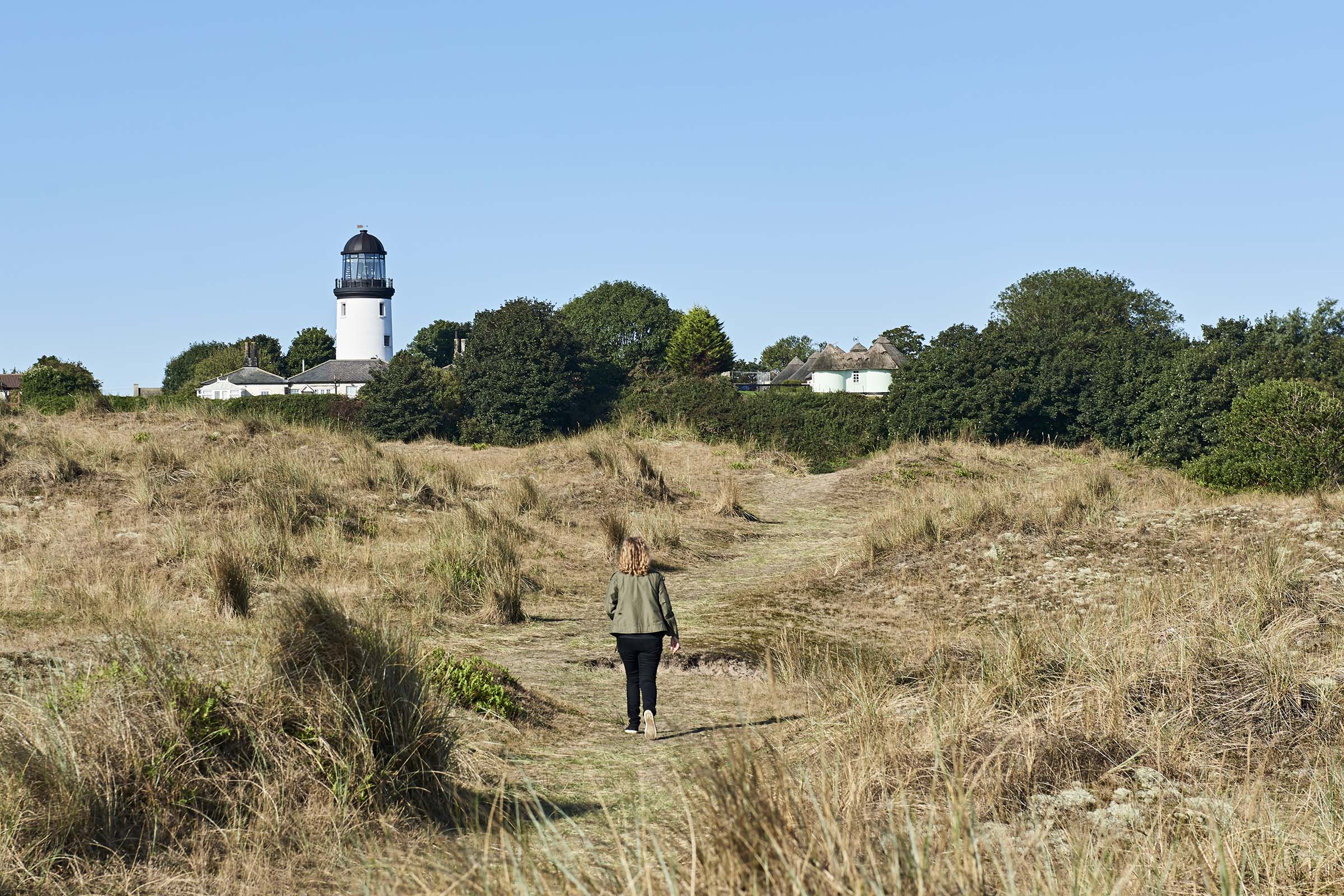 The restored Lighthouse is set back from the shoreline across the sand dunes.